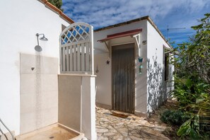 Ein weißes Gebäude mit Dusche, Tor und Tür.