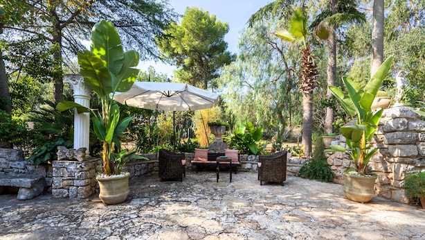 An outdoor patio with stone flooring, wicker furniture, and potted plants. - Villa Massa Depandance Apartment with Sea View, Wi-Fi and Air Conditioning (Polignano a Mare)