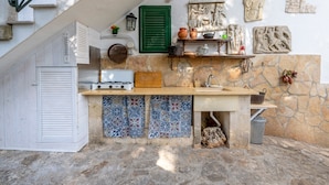 A compact kitchen with a built-in stove, a sink, and a stone wall with decorative tiles. - Villa Massa Depandance Apartment with Sea View, Wi-Fi and Air Conditioning (Polignano a Mare)