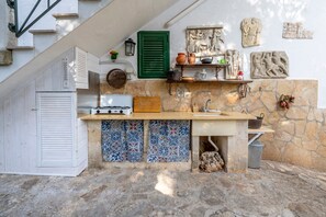 Een kleine keuken met een inbouwfornuis, een spoelbak en een stenen muur met decoratieve tegels.