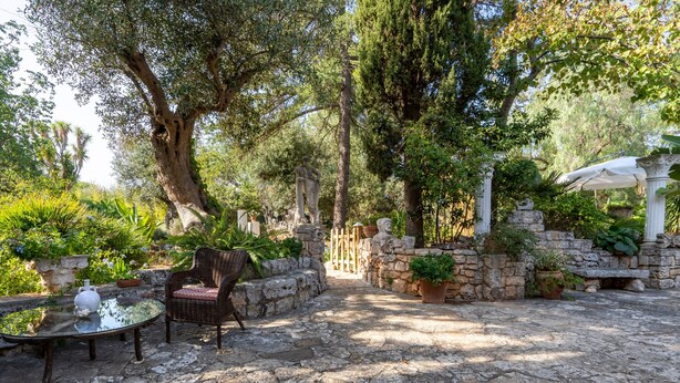 A stone patio with a wicker chair and a table, surrounded by potted plants and a stone wall. - Apartment 'Villa Massa' with Sea View, Wi-Fi and Air Conditioning (Polignano a Mare)