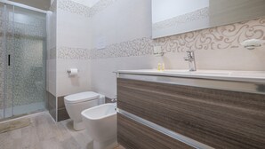 Ein modernes Badezimmer mit Dusche, Toilette, Bidet und Waschtisch mit Spiegel.