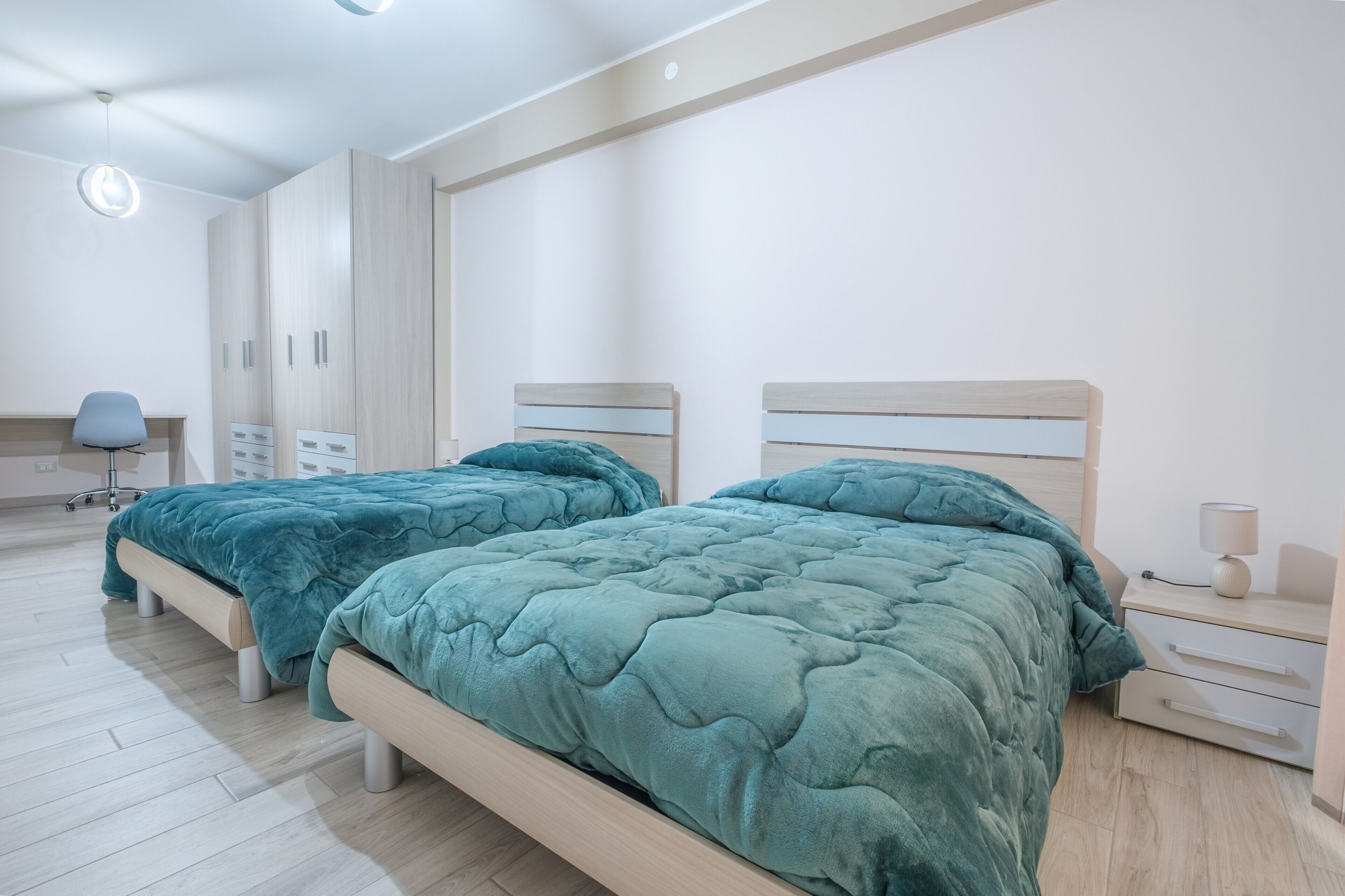Une chambre avec deux lits, un bureau, une chaise et une armoire.