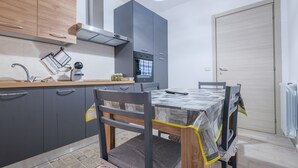 Eine moderne Küche mit grauen Schränken, einer Holz Arbeitsplatte, einem eingebauten Backofen und einem Esstisch mit Stühlen.