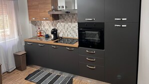 A modern kitchen with dark cabinetry, a built-in oven, and a coffee maker on the countertop.