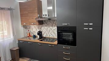 Una cucina moderna con mobili scuri, un forno integrato e una macchina da caffè sul piano di lavoro.