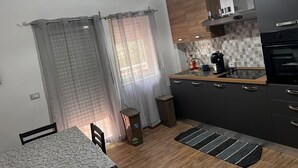 A compact kitchen with a dining area, a trash bin, and a small rug.