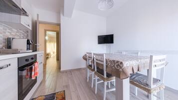 A modern kitchen with a built-in oven, a coffee machine, and a TV mounted on the wall.
