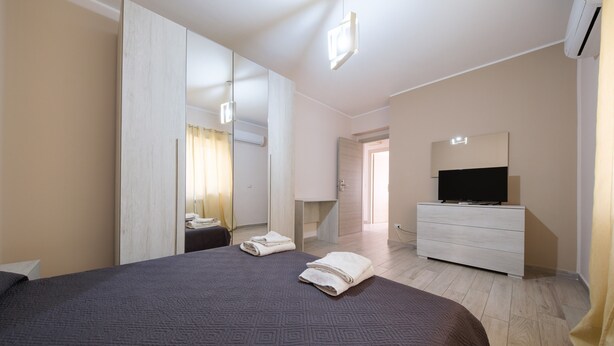 A hotel room with a large bed, a dresser, a TV, and a mirror.