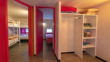 Una habitación con literas, un armario con espacio para colgar ropa y una estantería.