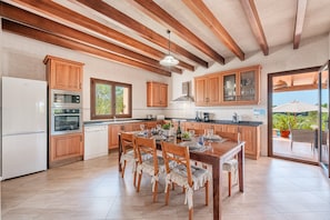 A kitchen with wooden cabinets, a dining table with chairs, and a view to the outside.