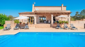 A house with a swimming pool, lounge chairs, and umbrellas. - Villa 'Can Rito Nou' with Mountain View, Wi-Fi and Air Conditioning (Felanitx)
