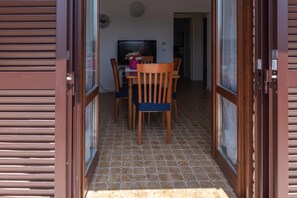 A room with a tiled floor, a wooden table with chairs, a television, and a door with a window. - Bed and Breakfast 'Dolce Alba' with Private Garden, Wi-Fi and Air Conditioning (Montecastrilli)