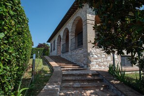 A stone building with a staircase leading to an entrance, surrounded by greenery. - Bed and Breakfast 'Dolce Alba' with Private Garden, Wi-Fi and Air Conditioning (Montecastrilli)