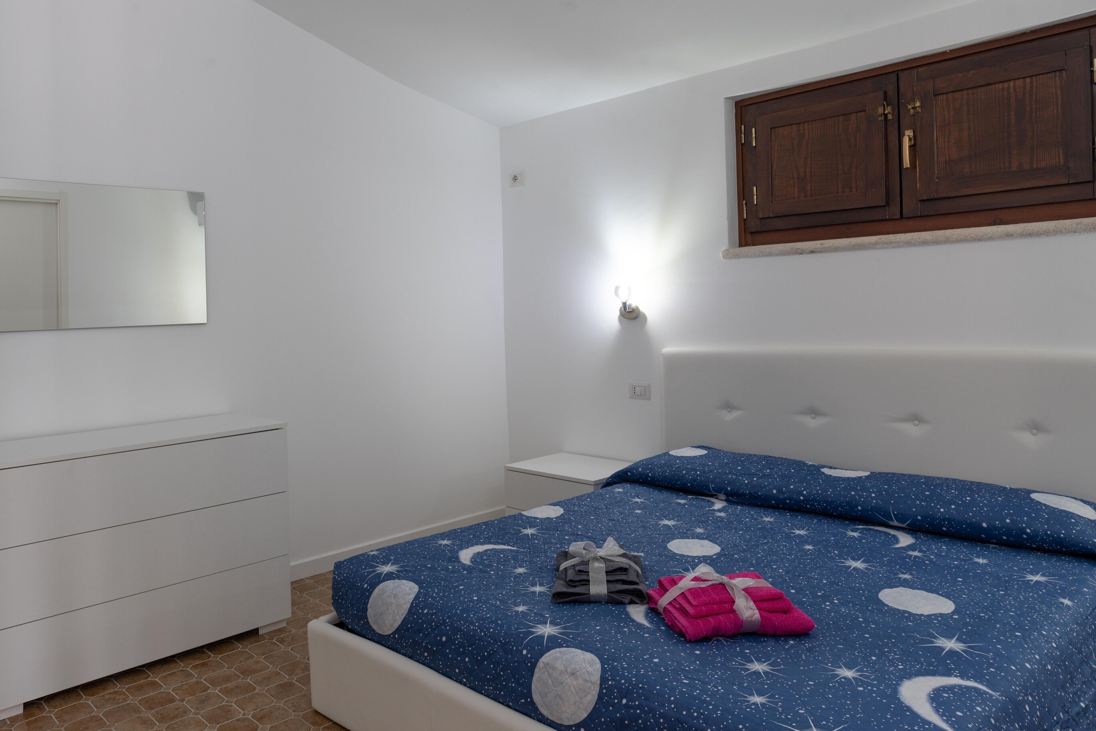 A bedroom with a bed, a dresser, a nightstand, and a wardrobe.