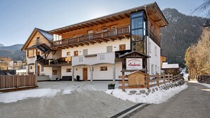 A multi-story building with a wooden facade, balconies, and a sign indicating 'Apartments Andreas.' - Apartment 'Antersi Robbi' with Mountain View, Shared Garden and Wi-Fi (St. Vigil Enneberg)