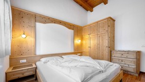 A bedroom with a wooden bed, a wooden dresser, and a wooden wardrobe. - Apartment 'Antersi Robbi' with Mountain View, Shared Garden and Wi-Fi (St. Vigil Enneberg)
