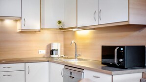 A modern kitchen with white cabinets, a coffee maker, a microwave, and a dishwasher. - Apartment 'Antersi Robbi' with Mountain View, Shared Garden and Wi-Fi (St. Vigil Enneberg)
