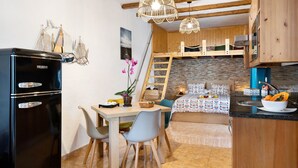 A compact kitchen with a refrigerator, dining table, chairs, and a ladder leading to a loft bed. - Holiday Home 'El Rinconcito De Jess' with Wi-Fi and Air Conditioning (El Golfo)