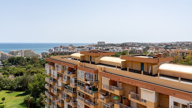 A multi-story residential building with balconies, a view of the sea, and a park in the foreground. - Apartment 'Aguila 900' with Private Terrace, Wi-Fi, and Air Conditioning (Benalmadena Arroyo de la Miel)