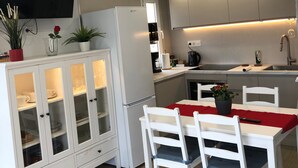 A modern kitchen with white cabinetry, a built-in oven, and a dining area with a table and chairs. - Apartment 'Aguila 900' with Private Terrace, Wi-Fi, and Air Conditioning (Benalmadena Arroyo de la Miel)