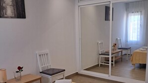 A bedroom with a bed, a chair, a small table, and a mirror reflecting another room. - Apartment 'Aguila 900' with Private Terrace, Wi-Fi, and Air Conditioning (Benalmadena Arroyo de la Miel)