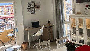 A room with a desk, chair, TV, artwork, and a balcony with a view of buildings. - Apartment 'Aguila 900' with Private Terrace, Wi-Fi, and Air Conditioning (Benalmadena Arroyo de la Miel)