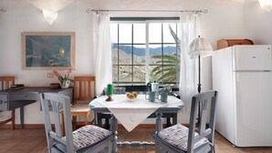 Eine Küche mit Esstisch, Stühlen, einem Kühlschrank und einem Fenster mit Bergblick.
