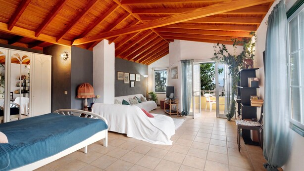 Ein Schlafzimmer mit Holzboden, einem Bett, einem Nachttisch, einem Fernseher und einem Fenster mit Vorhängen.