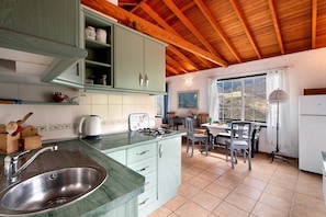 A kitchen with a sink, cabinets, and a dining area with chairs and a table.