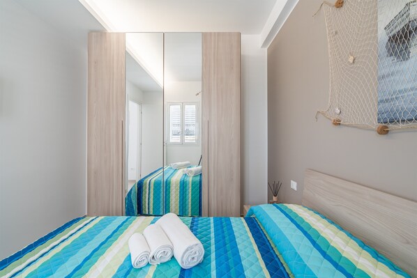 A bedroom with a bed, a mirror, and a netted wall decoration.