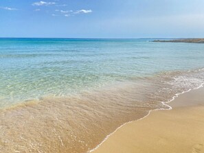 A beach with clear water and a sandy shore.