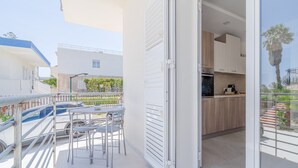 Um apartamento moderno com varanda, cozinha com armários de madeira e vista para uma palmeira.