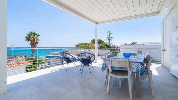 A covered outdoor dining area with a table and chairs, overlooking a clear blue sea. - Holiday Apartment "Greta Vista Mare" with Sea View, Private Terrace & Wi-Fi (Lido di Noto)