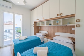 Une chambre d’hôtel avec deux lits, une tête de lit en bois, une petite table de chevet et un balcon avec vue.