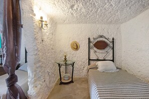 Une chambre à coucher avec un lit, une table de chevet avec une lampe, un chapeau accroché au mur et un plafond à motifs.