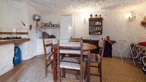 Una cocina rústica con una mesa de madera, sillas, una estufa y una puerta blanca.