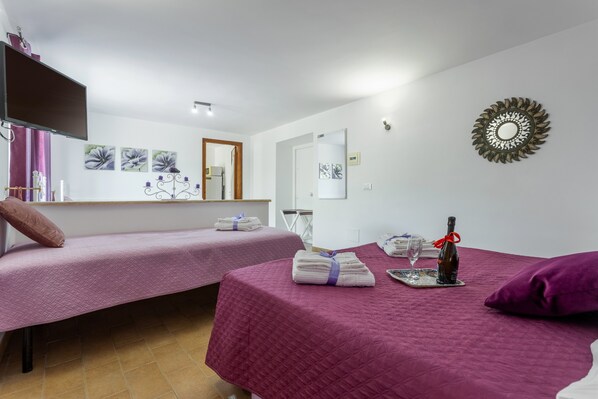 A room with two beds, a TV, artwork, a mirror, and a decorative wall piece.