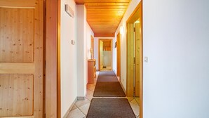 Un couloir avec des portes en bois, un sol carrelé et un plafond en bois.