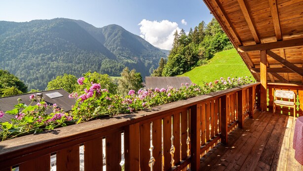 Une terrasse en bois offrant une vue sur les montagnes, avec une maison en arrière-plan.