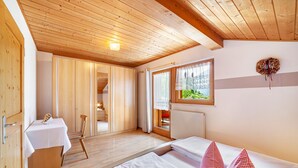 Un intérieur en bois avec un lit, une table et une fenêtre avec des rideaux.
