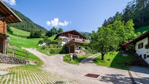 Un village rural avec une rue pavée, des maisons traditionnelles en bois et une chaîne de montagnes en arrière-plan.
