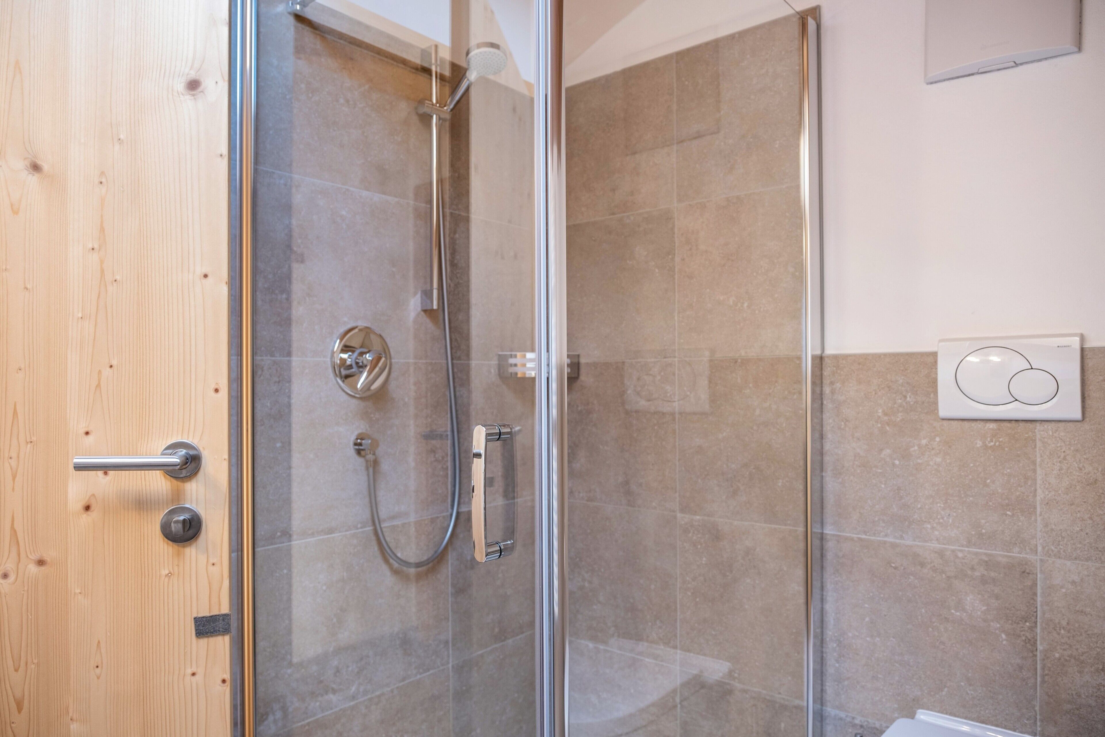 Eine Duschkabine mit Handbrause und verstellbarem Wasserhahn an der Wand.