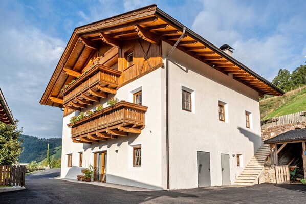 A two-story building with wooden balconies, a stone staircase, and a white exterior.
