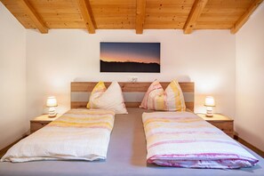A double room with two beds, wooden headboards, bedside lamps, and a sunset view.