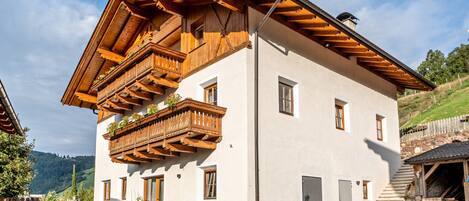 A two-story building with wooden balconies, a stone staircase, and a garage.