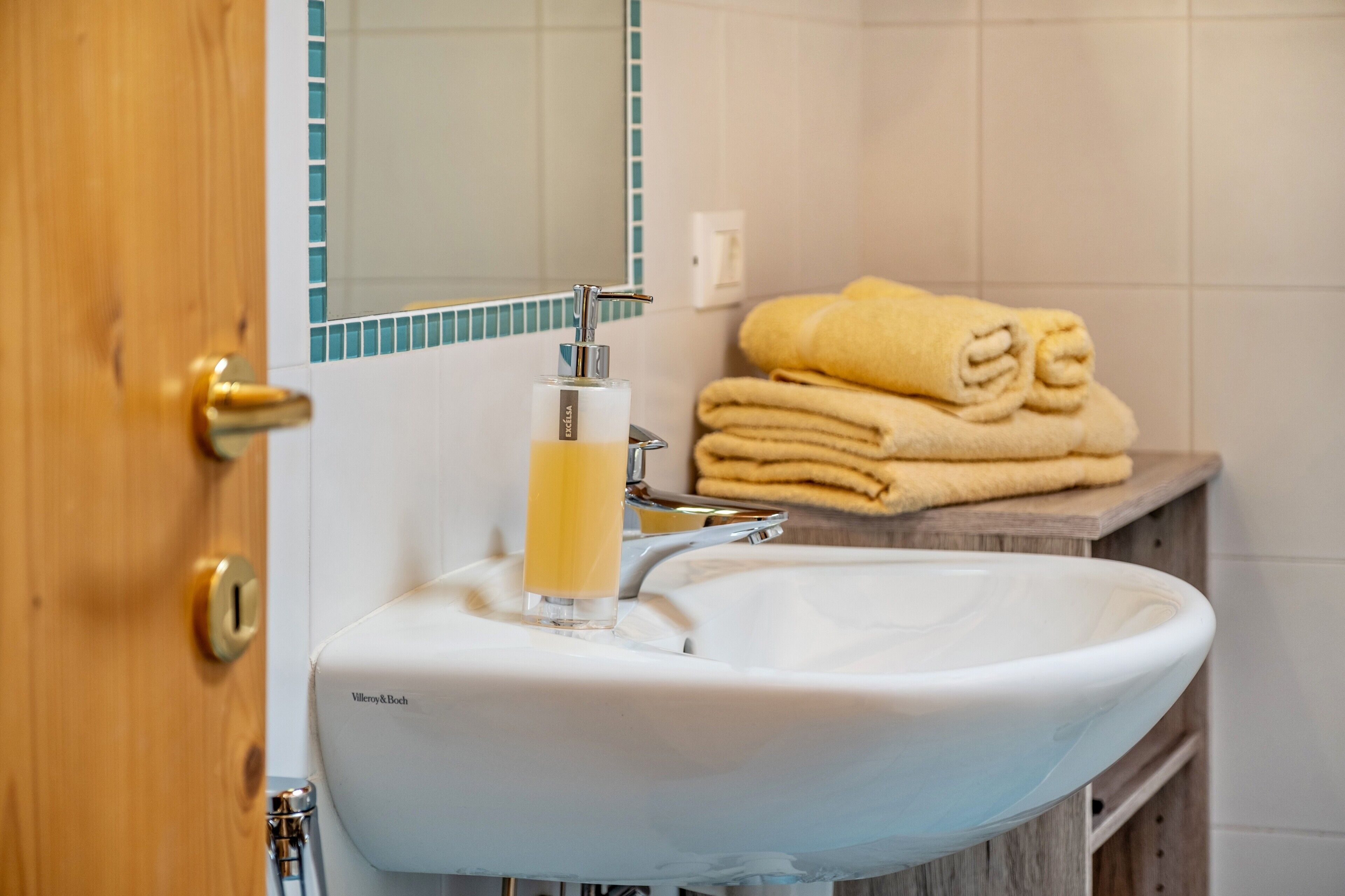 A bathroom with a white sink, a mirror, and a towel rack with folded towels.