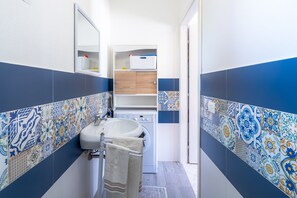 Une salle de bain équipée d’un lavabo, d’un miroir et d’un lave-linge.