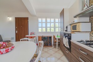 Uma cozinha com uma mesa de jantar, cadeiras, micro-ondas, forno e um armário.