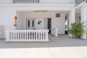 Un bâtiment blanc doté d’un balcon, de portes et d’une plante en pot.